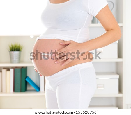 Pregnant woman applying stretch mark prevention lotion or moisturizer cream on belly, maternal skin care, 8 months pregnancy.