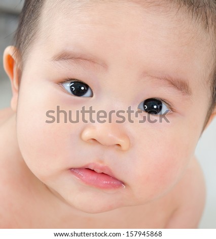 Close up face of six months old Asian baby boy with curious look