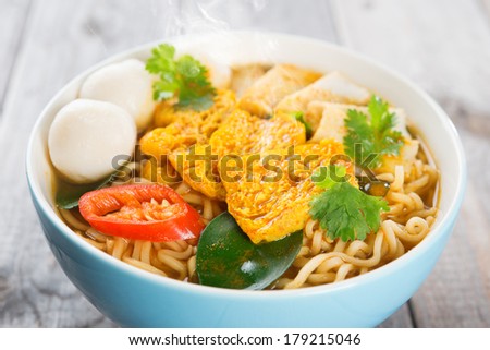 Close up spicy curry instant noodles. Asian cuisine, ready to serve on wooden dining table setting. Fresh hot with steamed smoke.