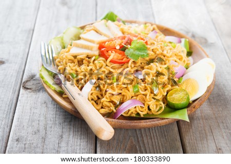 Spicy fried curry instant noodles or Malaysian style maggi goreng mamak.  Asian cuisine, ready to serve on wooden dining table setting. Fresh hot with steamed smoke.
