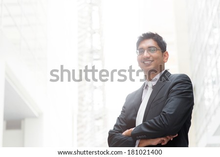 Portrait of happy and confident 30s Asian Indian businessman smiling. India male business man, real modern office building as background.
