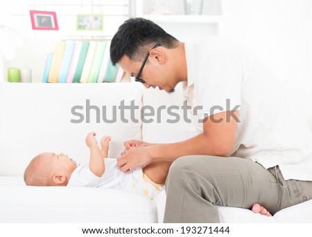 Young father changing diaper and clothes for baby boy. Asian family lifestyle at home.
