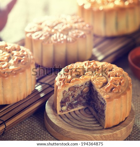 Retro vintage style Chinese mid autumn festival foods. Traditional mooncakes on table setting with teacup. The Chinese words on the mooncakes means assorted fruits nuts, not a logo or trademark.