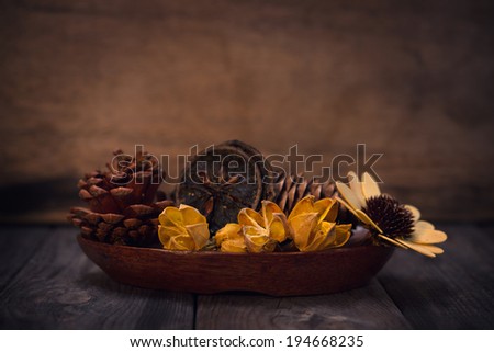 Aromatherapy concept. Dried flowers on wooden bowl in low light ambient setting.