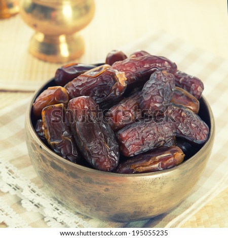 Dried date palm fruits or kurma, ramadan food which eaten in fasting month. Pile of fresh dried date fruits ready to eat in metal bowl.