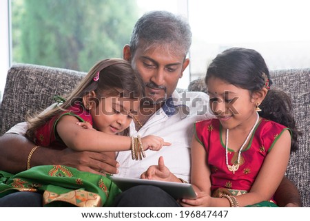 Indian family at home. Asian father and children using digital tablet computer, sitting on sofa, home schooling concept.