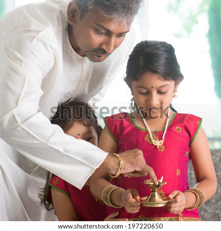 Indian family in traditional dress preparing to celebrate diwali or deepavali at home. Little girl hands holding oil lamp during festival of light.