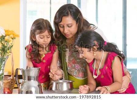 Asian family cooking food together at home. Indian mother and children preparing meal in kitchen. Traditional India people with sari clothing.