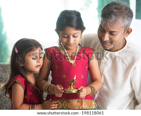 Indian family in traditional sari celebrate diwali or deepavali at home. Little girl hands holding oil lamp during festival of light.