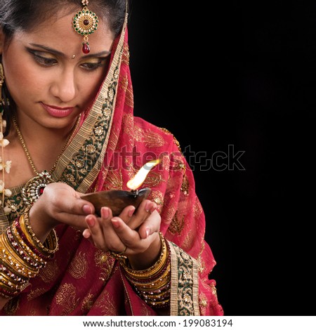 Beautiful Indian woman hands holding diya oil lamp, celebrating diwali festive of lights, traditional sari prayer isolated on black background with copy space on side.