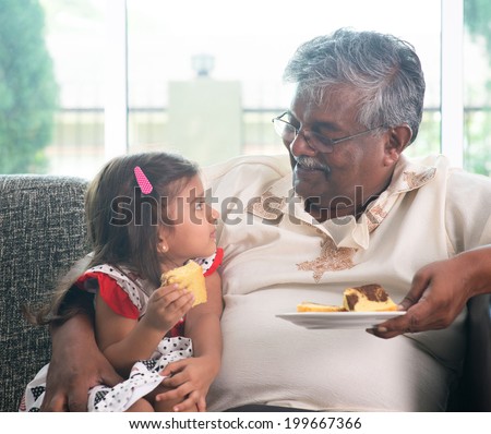 Portrait Indian family at home. Grandparent and grandchild eating cake. Asian people living lifestyle. Grandfather and granddaughter.