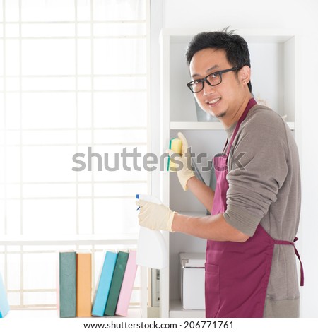 Asian man housekeeping. House husband doing house chores, with home interiors.