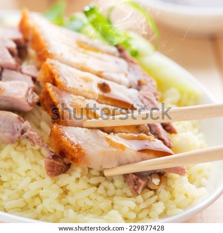 Chinese roasted pork served with soy and seafood sauce. Hong Kong cuisine. Close up on meat and chopsticks. Fresh cooked with hot steam and smoke.