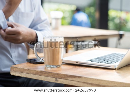 Asian Indian businessman having a cup hot milk tea and rolled up his sleeve during office break.