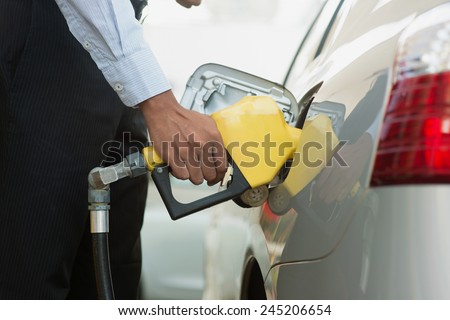 Pumping gas. Close up of man pumping gasoline fuel in car at gas station.
