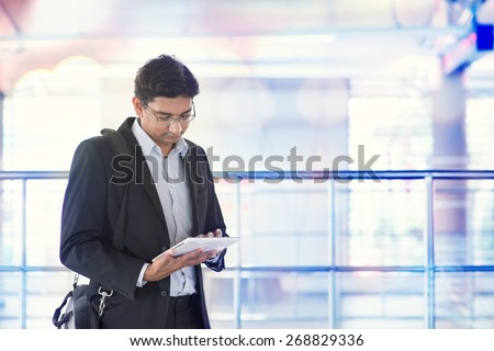 Indian business man using tablet computer while waiting train at railway station.