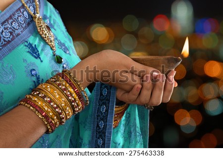 Diwali or festive of lights. Traditional Indian festival, woman in sari hands holding oil lamp, copy space at side.