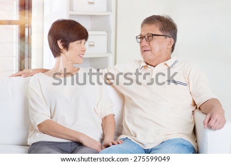 Senior couple having conversation, sitting on sofa at home. Living lifestyle of Asian family.