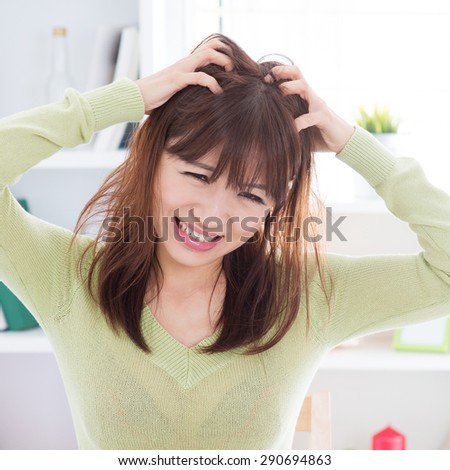 Asian woman scratching itchy head with frustrate face expression, female having hair problems.