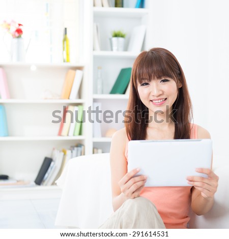 Happy Asian girl using social media with tablet computer, social networks concept. Young woman indoors living lifestyle at home.