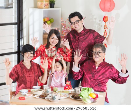 Chinese New Year, reunion dinner. Happy Asian Chinese multi generation family with red cheongsam dining at home.