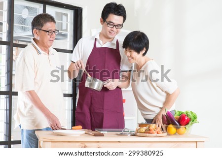 Asian adult son preparing meal for his senior parents at kitchen. Family living lifestyle at home.