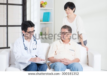 Doctor and patient. Asian senior couple consult family doctor, sitting on sofa. Senior retiree indoors living lifestyle.