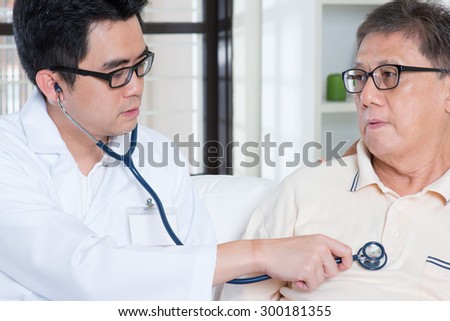 Doctor and patient. Sick Asian elder man consult family doctor, sitting on sofa. Senior retiree indoors living lifestyle.