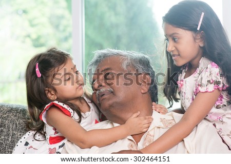 Happy Indian family at home. Asian grandfather and granddaughters having sweet conversation. Grandparent and grandchildren indoor lifestyle.