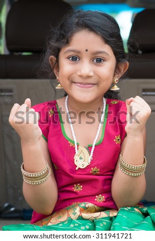 Excited Indian girl sitting in car smiling, ready to vacation. Asian child in traditional dress.