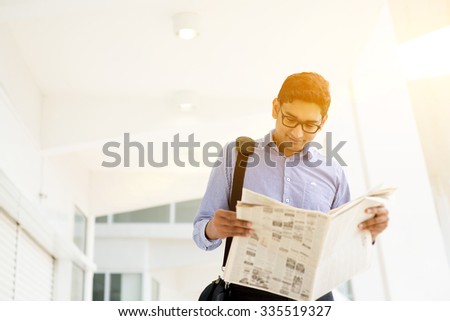 Asian Indian businessman reading newspaper on the way to work in a morning. Handsome male model.
