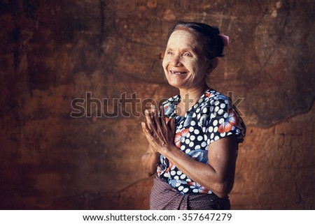 Portrait of traditional Asian Burmese woman greeting, standing inside a temple, low light, Bagan, Myanmar