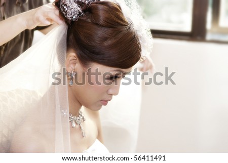 Asian bride having hairdo on her wedding day