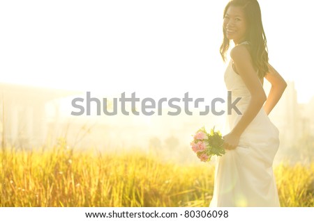 Asian bride at outdoor in a morning surrounding by golden sunlight