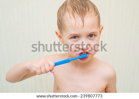 Blond boy brushing his teeth in the bathroom blue brush