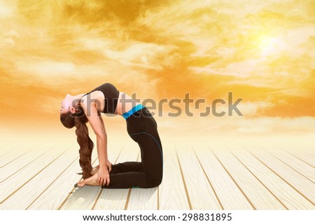 Young woman doing yoga exercise on wood floor at sunset