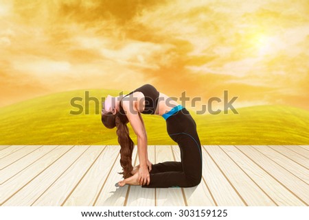 Young woman doing yoga exercise on wood floor with field at sunset