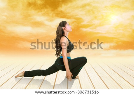 Young woman doing yoga exercise on wood floor at sunset