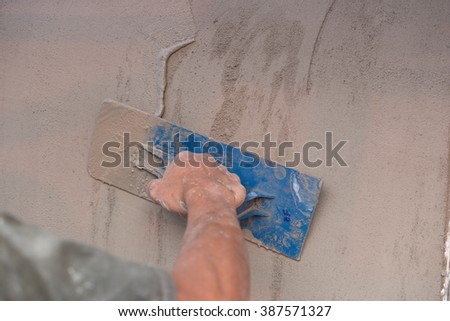 hand of builder worker use trowel plastering concrete at wall
