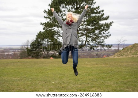 Naturally blond girl with curly hair, jumping outside