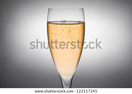 flute of champagne with gold bubbles on a grey background