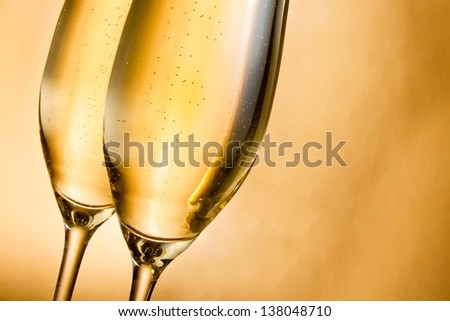 flutes of champagne with golden bubbles against golden background