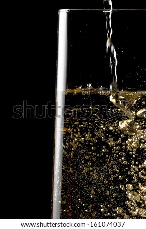 flute of champagne with golden bubbles on black background and space for text