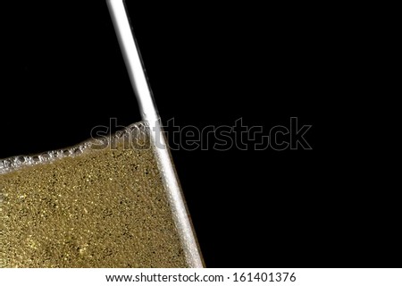 high detail of one flute tilted of champagne with golden bubbles on black background