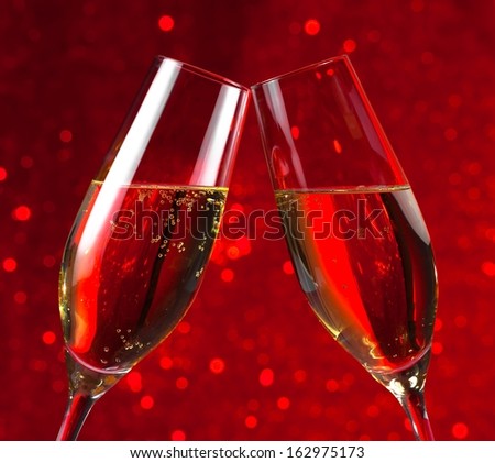 pair of a champagne flutes make cheers on red light bokeh background