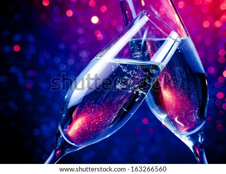 Pair Of Champagne Flutes With Gold Bubbles Make Cheers On Blue Tint Light Bokeh Background