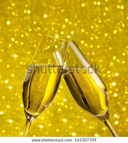champagne flutes with golden bubbles make cheers on golden light bokeh background