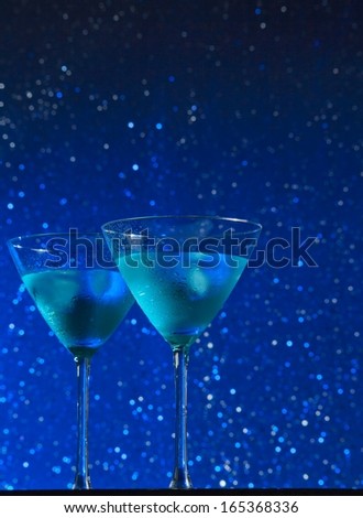 view from below of glasses of fresh blue cocktail with ice on blue tint light bokeh background like sky with star with space for text