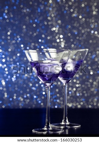 glasses of fresh cocktail with ice on blue tint light bokeh background on bar table