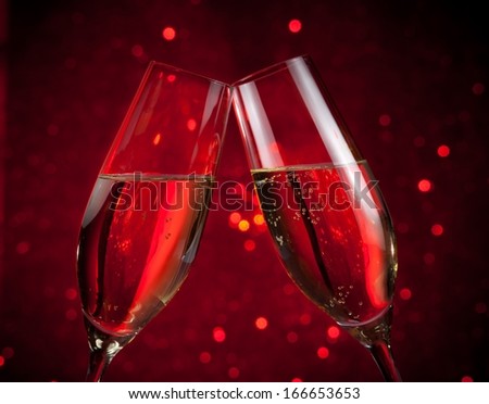 two champagne flutes make cheers on red dark light bokeh background, valentine and christmas events
